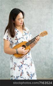 Happy woman musician playing ukulele and singing a song in sound studio. Music lifestyle concept.
