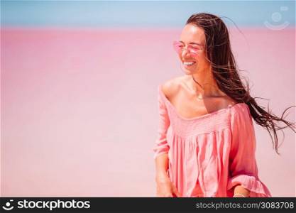 Happy woman on a pink salt lake on a sunny summer day.. Woman in hat walk on a pink salt lake on a sunny summer day.