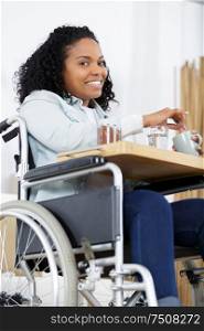 happy woman on a wheelchair eating dinner at home