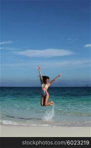 Happy woman on beach. Beautiful happy woman in bikni jump on tropical beach