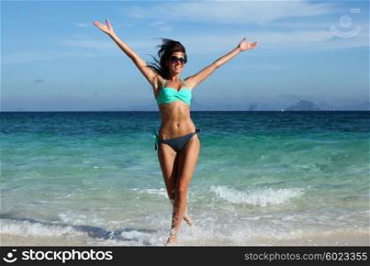 Happy woman on beach. Beautiful happy woman in bikni run on tropical beach