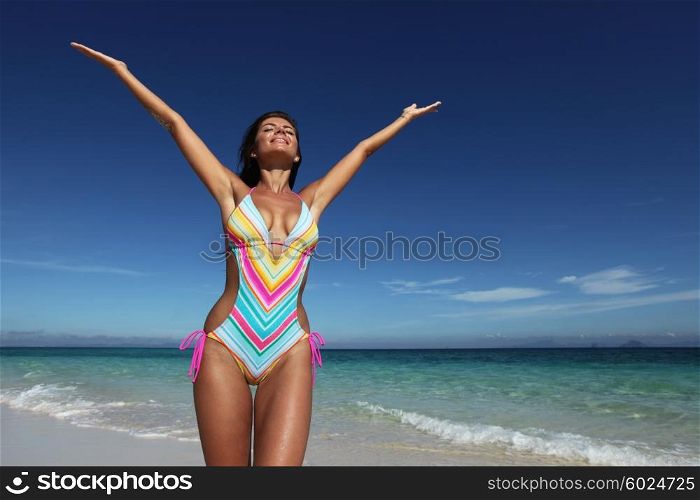Happy woman on beach. Beautiful happy woman in bikni with raised hands on tropical beach