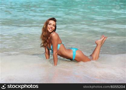 Happy woman on beach. Young happy woman laying on a beach and enjoying water