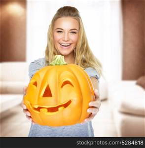 Happy woman on Halloween party at home, holding in hands pumpkin with carved face, having fun on traditional autumn holiday