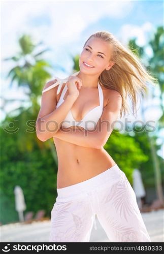 Happy woman on the beach posing with beautiful starfish, enjoying active summer vacation on exotic island, pleasure and wellness concept