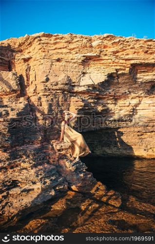 Happy woman on the cliff have fun in the sea. Tourist woman outdoor on edge of cliff seashore