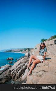 Happy woman on the cliff have fun in the sea. Tourist woman outdoor on edge of cliff seashore