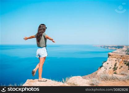 Happy woman on vacation on edge of cliff. Tourist woman outdoor on edge of cliff seashore