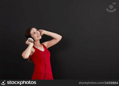 Happy woman over a black background listen music with headphones