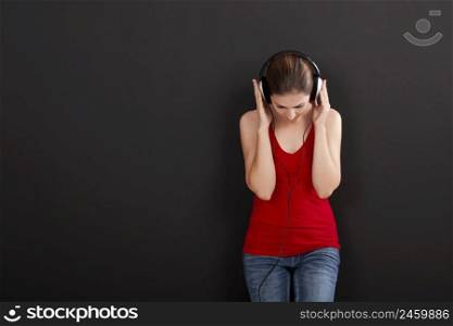 Happy woman over a black background listen music with headphones