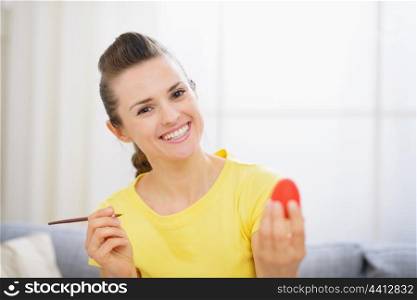 Happy woman painting on Easter egg
