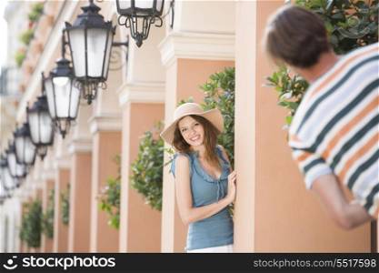 Happy woman playing hide-and-seek with man amongst pillars