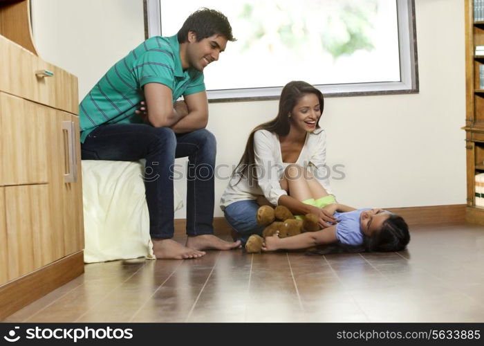 Happy woman playing with daughter while man sitting besides