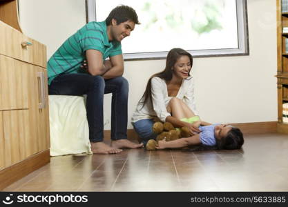 Happy woman playing with daughter while man sitting besides