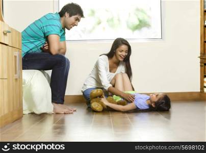 Happy woman playing with daughter while man sitting besides