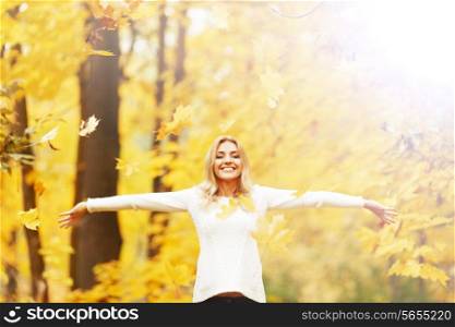 Happy woman posing in autumn park on yellow trees background