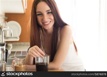 Happy woman preparing coffee in her kitchen