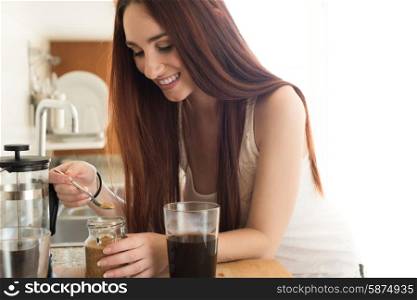Happy woman preparing coffee in her kitchen