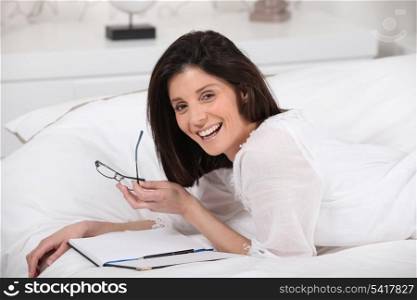 Happy woman reading in bed
