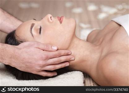 Happy woman receiving head massage over bamboo mat