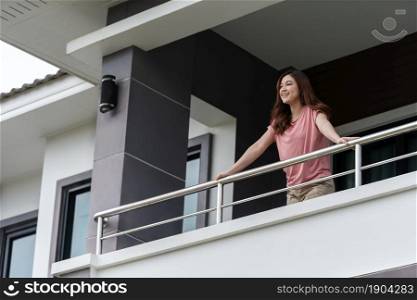 happy woman relaxing and looking from balcony of her home