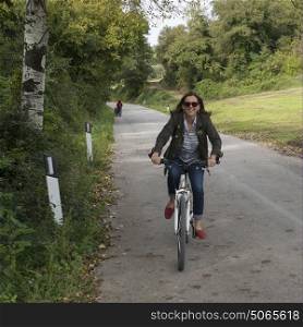 Happy woman riding a bicycle on country road, Chianti, Tuscany, Italy