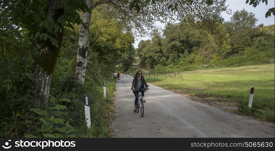 Happy woman riding a bicycle on country road, Chianti, Tuscany, Italy