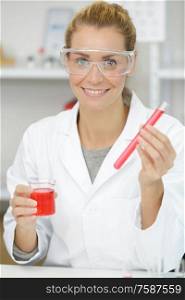 happy woman scientist adding liquid to test tube