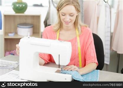 happy woman sewing on sewing-machine