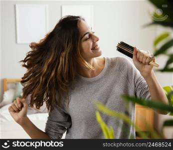 happy woman singing into hairbrush home