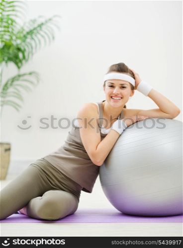 Happy woman sitting near fitness ball