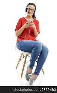 Happy woman sitting on a chair and listen music on her phone, isolated over white background