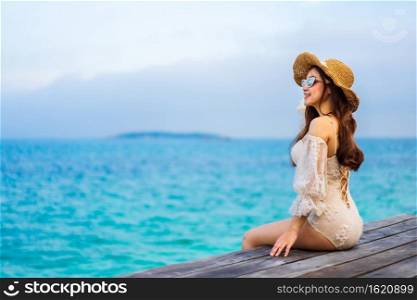 happy woman sitting on a wooden bridge in the sea beach at Koh MunNork Island, Rayong, Thailand 