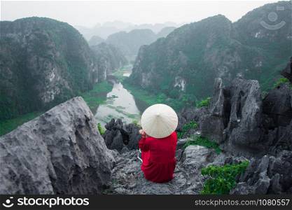 happy woman sitting on peak of mountain at Mua Cave, Ninh Binh, Vietnam at evening, subject is blurred, low key and noise.