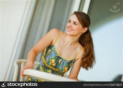 Happy woman sitting on terrace and looking in corner