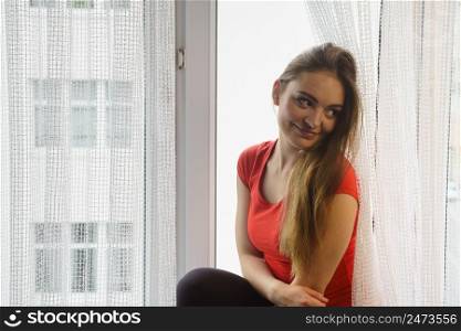 Happy woman sitting on windowsill, energizing morning thinking about day, relaxing having good time.. Happy woman sitting on windowsill, energizing morning