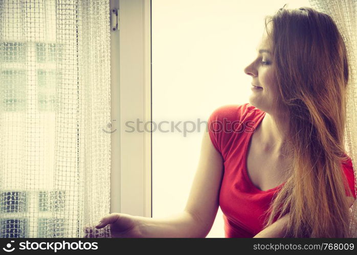 Happy woman sitting on windowsill, energizing morning thinking about day, relaxing having good time.. Happy woman sitting on windowsill, energizing morning