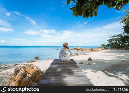 happy woman sitting on wood bridge with view of the sea, soft focus with noise