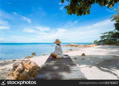 happy woman sitting on wood bridge with view of the sea, soft focus with noise