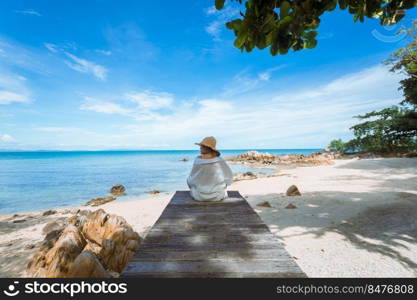 happy woman sitting on wood bridge with view of the sea, soft focus with noise