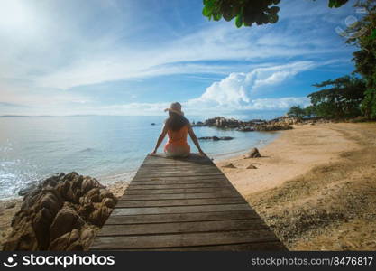 happy woman sitting on wood bridge with view of the sea, soft focus with noise