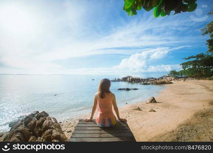 happy woman sitting on wood bridge with view of the sea, soft focus with noise