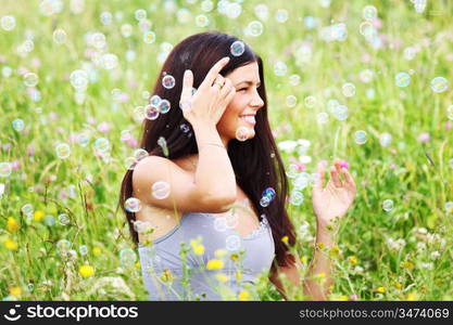 happy woman smile in green grass soap bubbles around