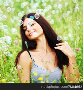 Happy woman smile in green grass soap bubbles around. Brew on grass