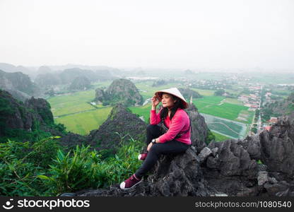 happy woman stand on peak of mountain at Mua Cave, Ninh Binh, Vietnam at evening, subject is blurred, low key and noise.