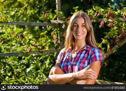 Happy woman standing in her garden in summer on a wonderful sunny day