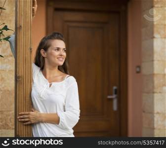 Happy woman standing on doorstep and looking on copy space