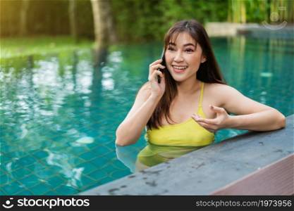 happy woman talking on mobile phone in the swimming pool