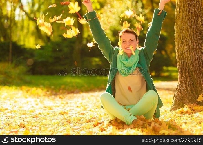 Happy woman throwing autumn leaves in park during beautiful sunny autumnal weather.. Happy woman throwing autumn leaves in park