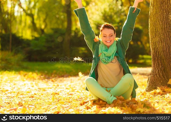 Happy woman throwing autumn leaves in park during beautiful sunny autumnal weather.. Happy woman throwing autumn leaves in park
